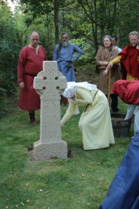 Gytha adds a handful of soil to the base of Kim's cross. Everyone present added theirs before it was filled in.
